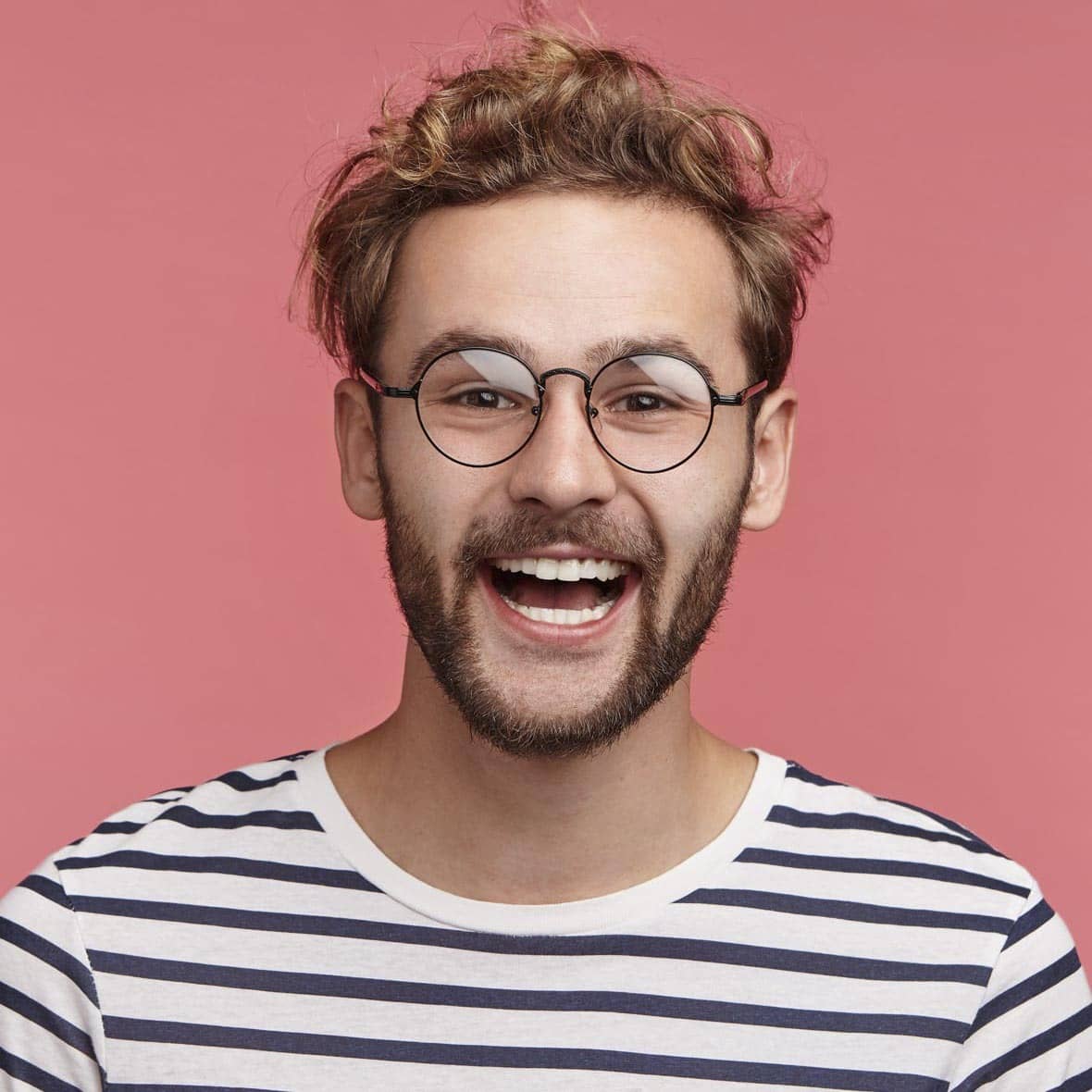 Chico de cabello rizado rubio con gafas sonriendo