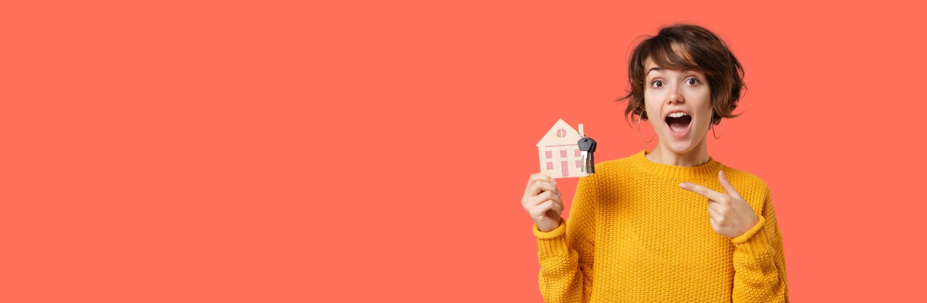 Mujer sonriente con jersey amarillo de punto sosteniendo las llaves de su nuevo piso